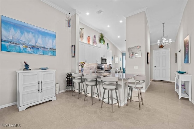 kitchen with a kitchen breakfast bar, visible vents, appliances with stainless steel finishes, and ornamental molding