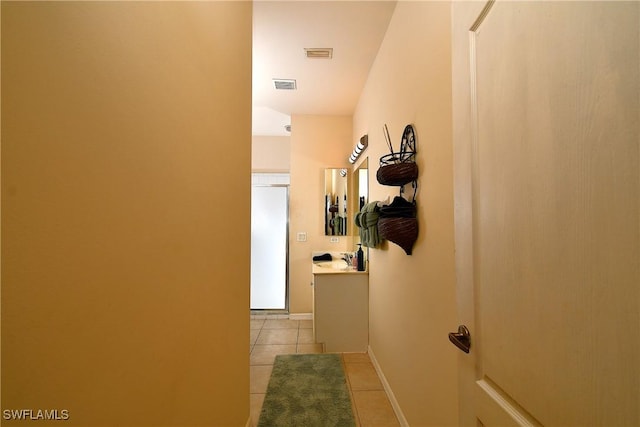 corridor with light tile patterned floors, visible vents, and baseboards