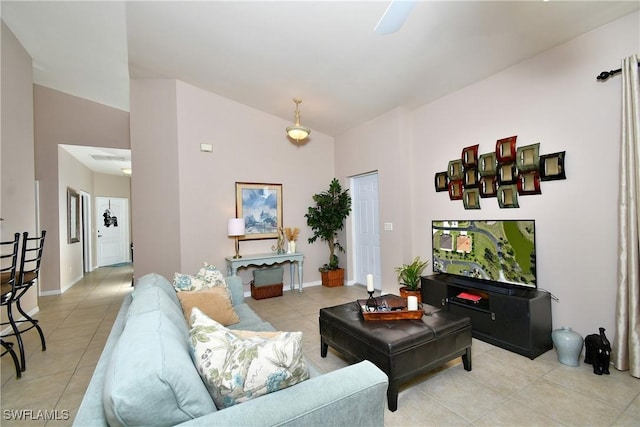 living area with baseboards, light tile patterned flooring, and vaulted ceiling