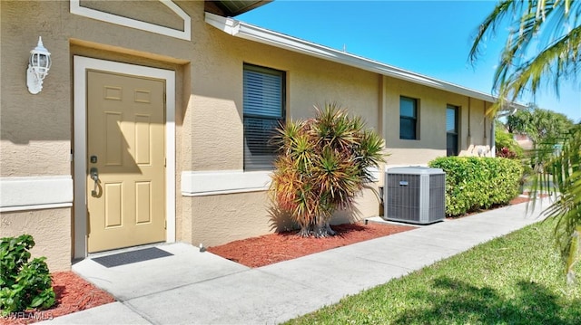 property entrance with stucco siding and central AC