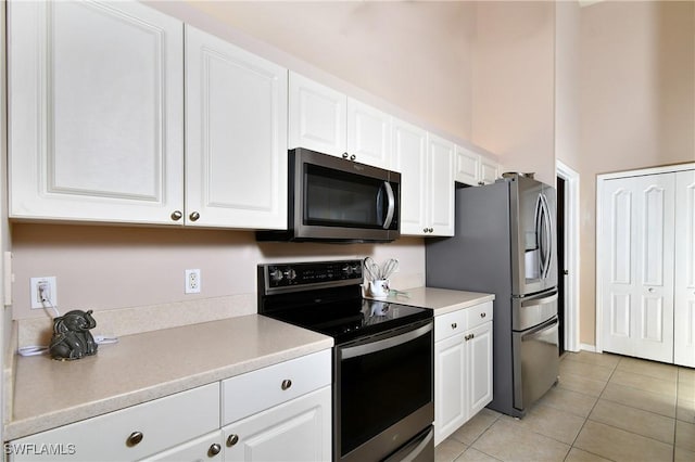 kitchen with light countertops, white cabinets, light tile patterned floors, and stainless steel appliances