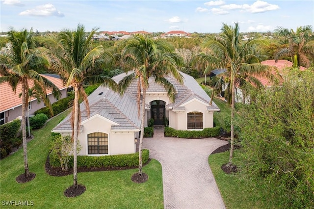 view of front of house with stucco siding, decorative driveway, and a front lawn