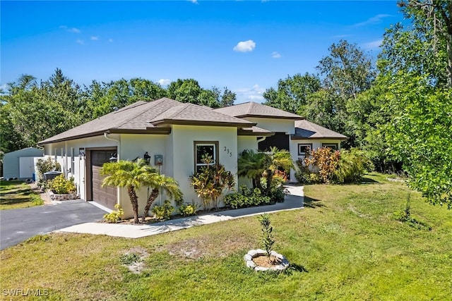 view of front of home with a front yard, driveway, an attached garage, a shingled roof, and stucco siding