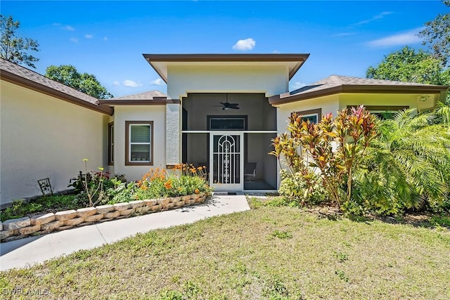 entrance to property featuring stucco siding, a lawn, and a garage