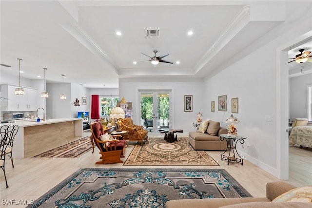 living room with visible vents, a tray ceiling, french doors, crown molding, and ceiling fan