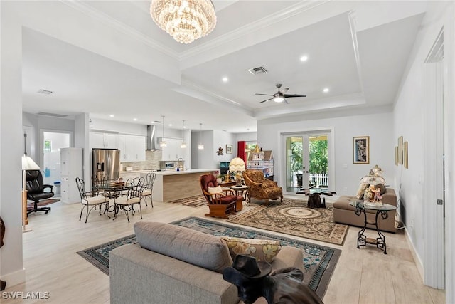 living room with visible vents, light wood-type flooring, a raised ceiling, and ornamental molding