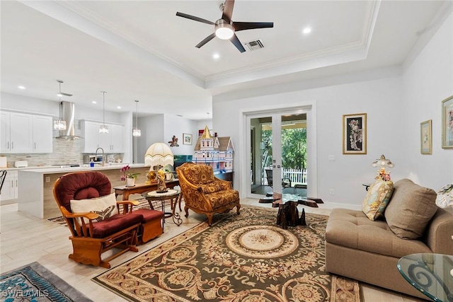 living room with visible vents, a tray ceiling, and ornamental molding