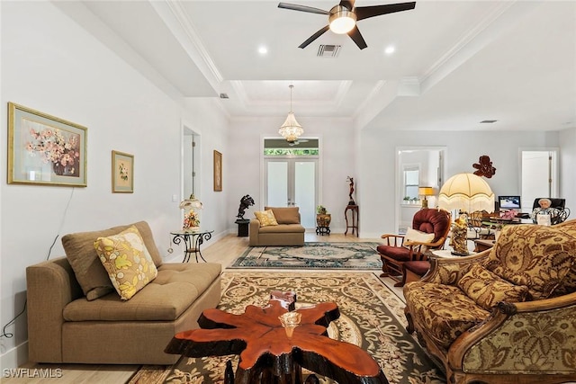 living room with visible vents, ornamental molding, a ceiling fan, baseboards, and a raised ceiling