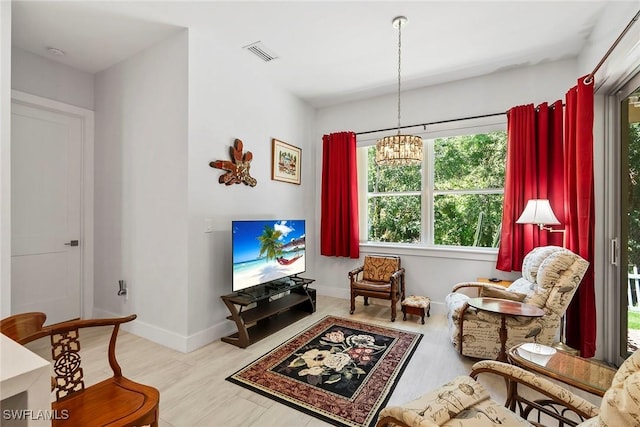 sitting room with a chandelier, visible vents, baseboards, and wood finished floors