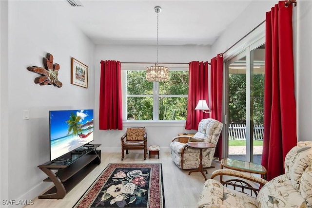 living area featuring baseboards, an inviting chandelier, and wood finished floors