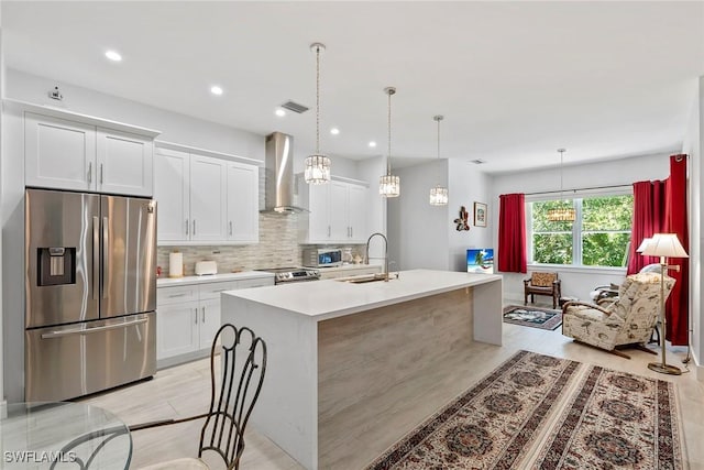 kitchen featuring visible vents, a sink, wall chimney range hood, appliances with stainless steel finishes, and light countertops