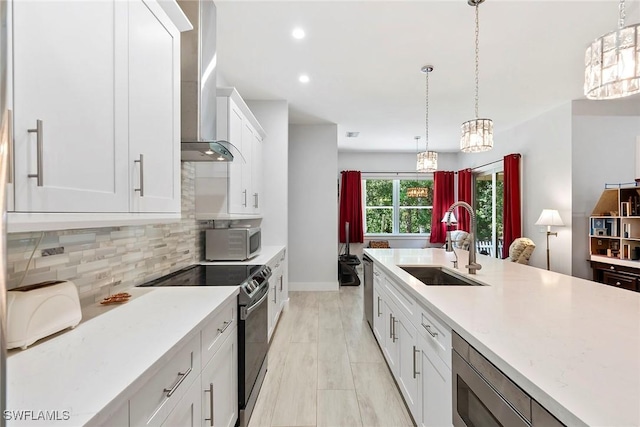 kitchen featuring electric range, a sink, hanging light fixtures, wall chimney exhaust hood, and backsplash