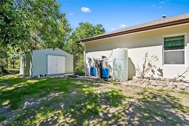 exterior space featuring a storage shed, an outbuilding, a lawn, and stucco siding