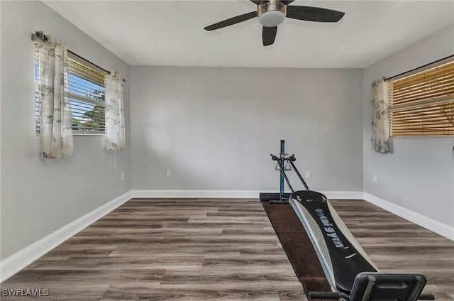 exercise area featuring wood finished floors, baseboards, and ceiling fan