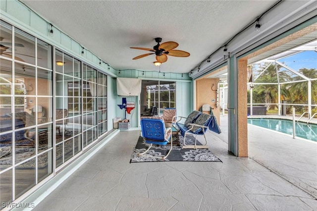 sunroom / solarium featuring rail lighting and ceiling fan