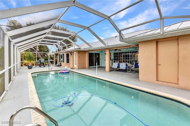 outdoor pool with glass enclosure, a ceiling fan, and a patio