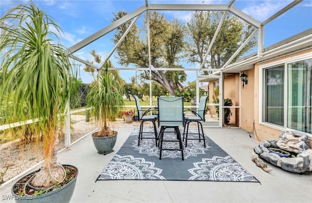 view of patio with outdoor dining space, glass enclosure, and a fire pit