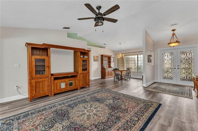 foyer with visible vents, lofted ceiling, ceiling fan with notable chandelier, french doors, and wood finished floors