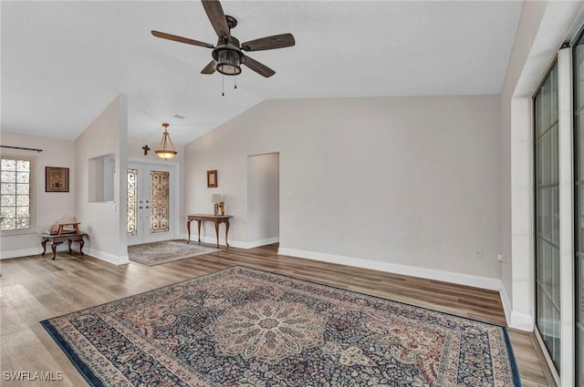 living room with french doors, lofted ceiling, baseboards, and wood finished floors