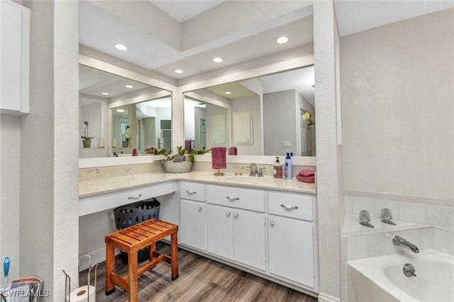 bathroom with vanity, a garden tub, recessed lighting, and wood finished floors