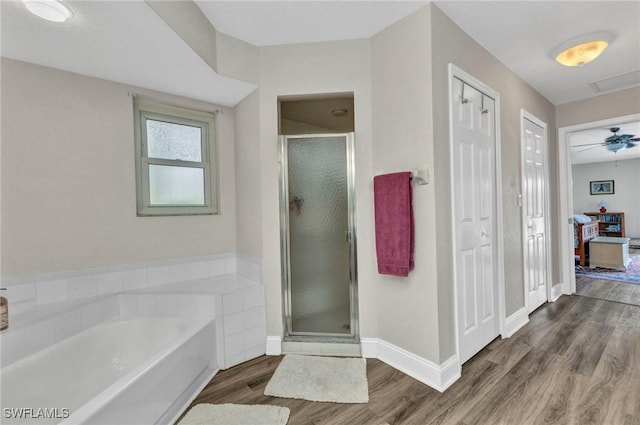 full bathroom featuring a shower stall, a bath, wood finished floors, and baseboards