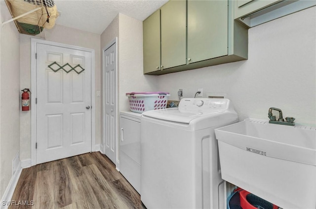 laundry area featuring a sink, dark wood-style floors, cabinet space, separate washer and dryer, and baseboards