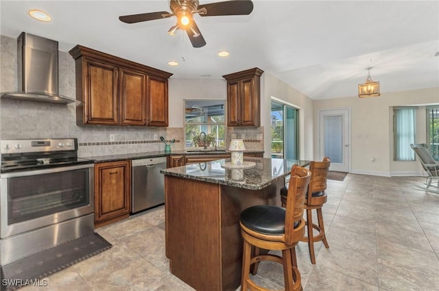 kitchen with backsplash, a center island, wall chimney range hood, appliances with stainless steel finishes, and a sink