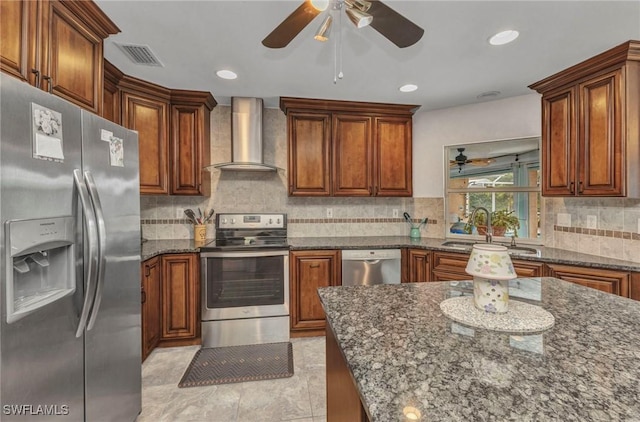 kitchen featuring dark stone countertops, visible vents, a sink, appliances with stainless steel finishes, and wall chimney range hood