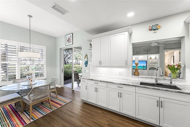 kitchen with visible vents, dark wood-style flooring, a sink, decorative backsplash, and white cabinetry