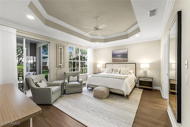 bedroom with a tray ceiling, visible vents, dark wood-style floors, and access to outside