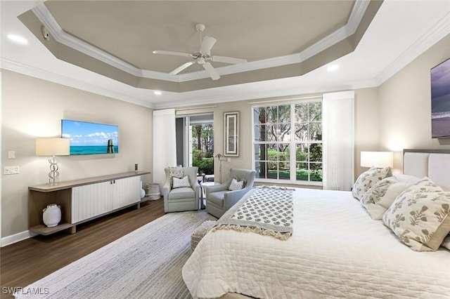 bedroom featuring crown molding, baseboards, wood finished floors, a raised ceiling, and a ceiling fan