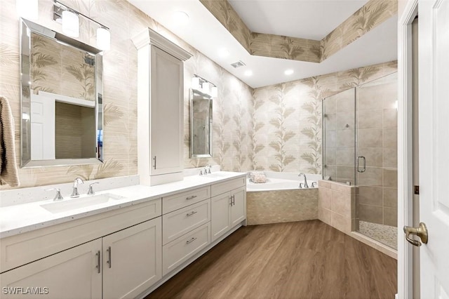 bathroom with wood finished floors, double vanity, a stall shower, a sink, and a bath