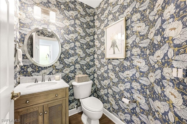 bathroom featuring vanity, toilet, baseboards, and wallpapered walls