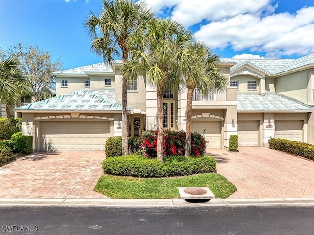 view of property with stucco siding, driveway, and an attached garage