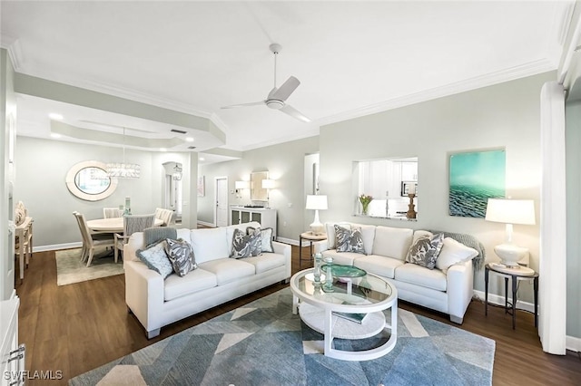 living area with a tray ceiling, baseboards, ornamental molding, and dark wood-style flooring