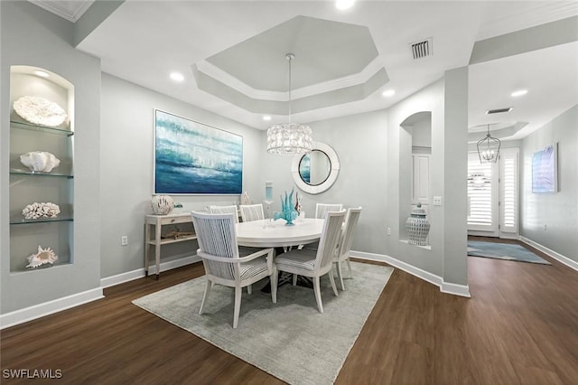 dining space with a chandelier, visible vents, a raised ceiling, and wood finished floors