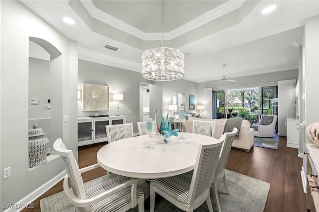 dining area with a tray ceiling, visible vents, ceiling fan, and dark wood-style flooring