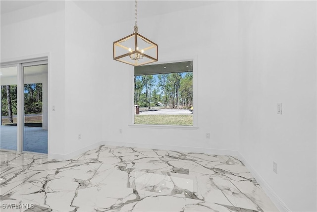 empty room with an inviting chandelier, marble finish floor, and baseboards
