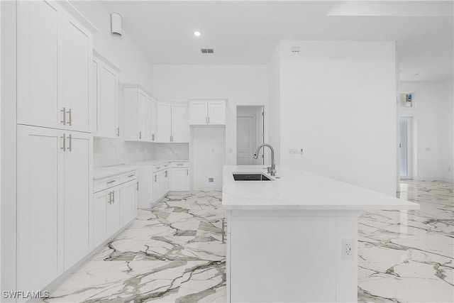 kitchen with visible vents, an island with sink, marble finish floor, white cabinetry, and a sink