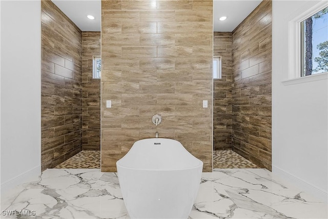 full bath with marble finish floor, a walk in shower, and a freestanding tub