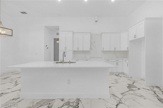 kitchen with white cabinetry, a center island with sink, visible vents, and a sink