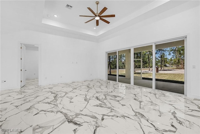 empty room featuring visible vents, ceiling fan, recessed lighting, a high ceiling, and a raised ceiling