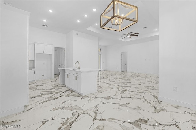 kitchen with visible vents, white cabinetry, open floor plan, and a sink