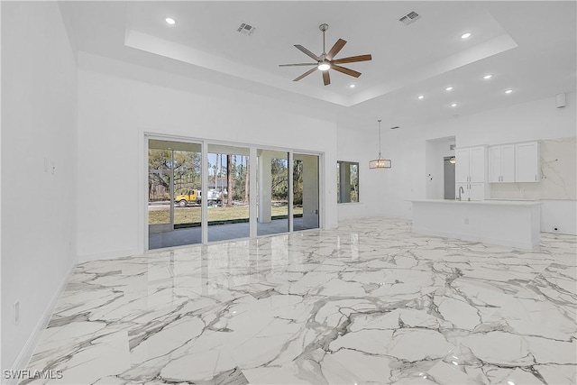 unfurnished living room with a raised ceiling, recessed lighting, visible vents, and a towering ceiling