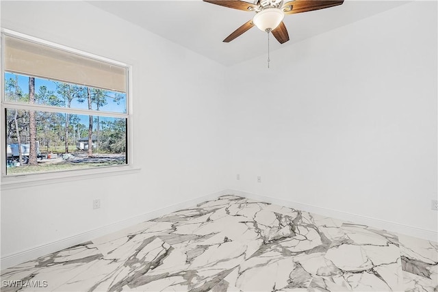 spare room featuring a ceiling fan and baseboards