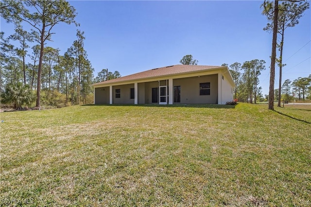 back of property with a yard and stucco siding