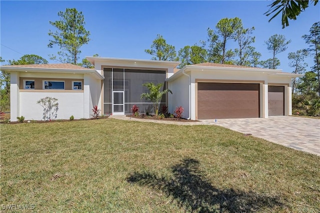 view of front of house featuring a front lawn, stucco siding, decorative driveway, a garage, and a sunroom