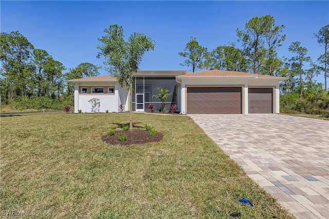 view of front of home with a front yard, stucco siding, decorative driveway, a sunroom, and an attached garage