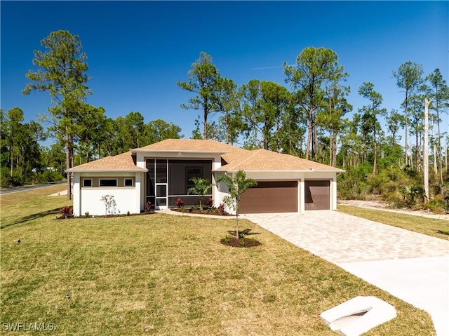 view of front of home with decorative driveway, a garage, a front yard, and a sunroom