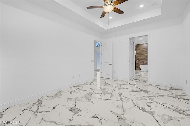 empty room with recessed lighting, a ceiling fan, a raised ceiling, and baseboards